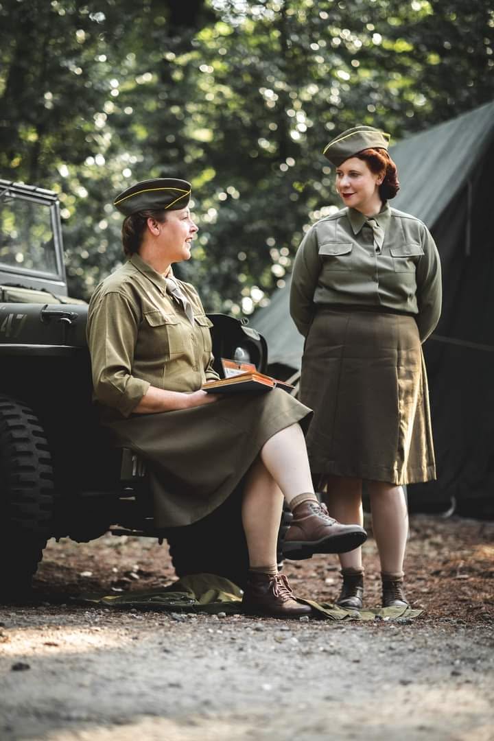 Two WAC reenactors talking beside a Jeep